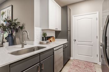 a kitchen with a sink and a door to a refrigerator at Alexandria of Carmel Apartments, Carmel, IN